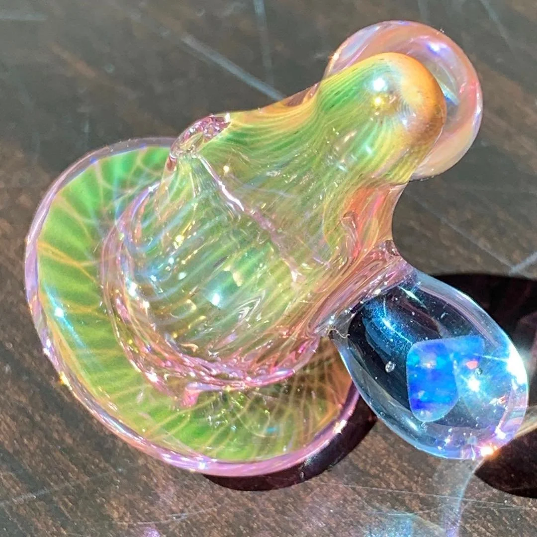 Colorful, iridescent glass art piece on a dark surface.