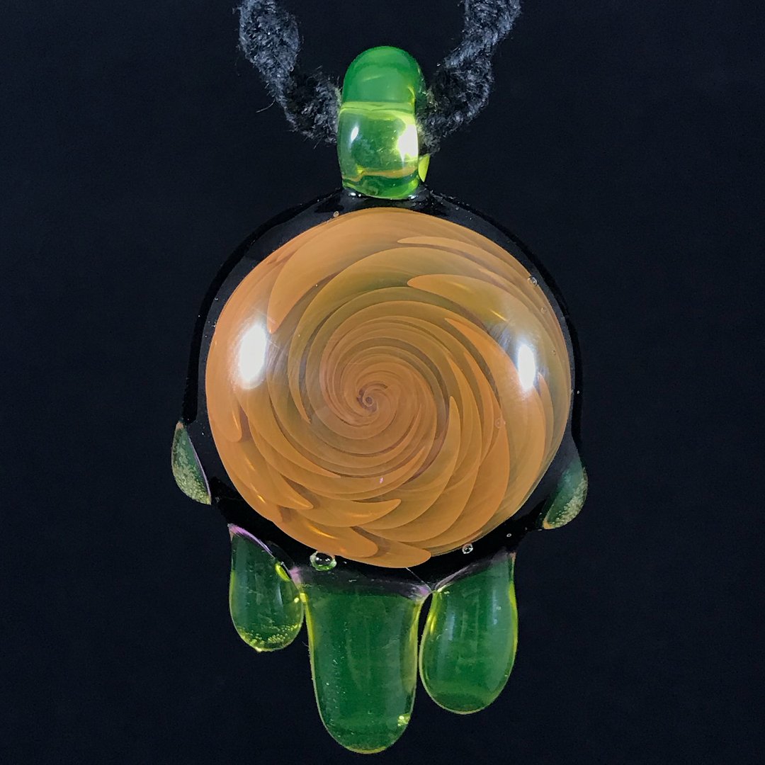 Frog-shaped pendant with a spiral swirl pattern in the center, made of glass with green accents, hanging on a black cord