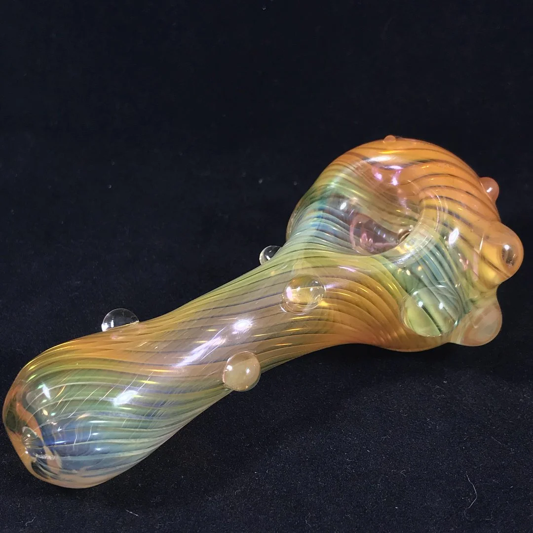 Colorful glass pipe with a swirling pattern and small bubble details, resting on a black surface.