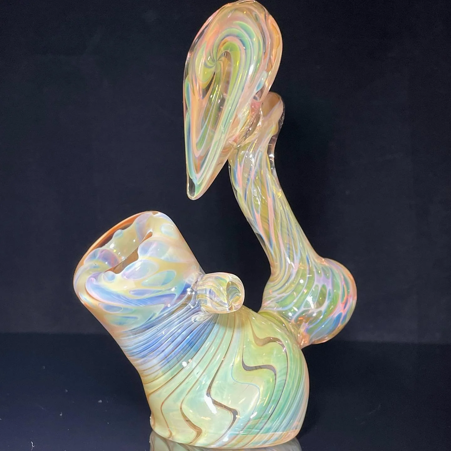 Iridescent glass sculpture with flowing, abstract shapes on a dark background.