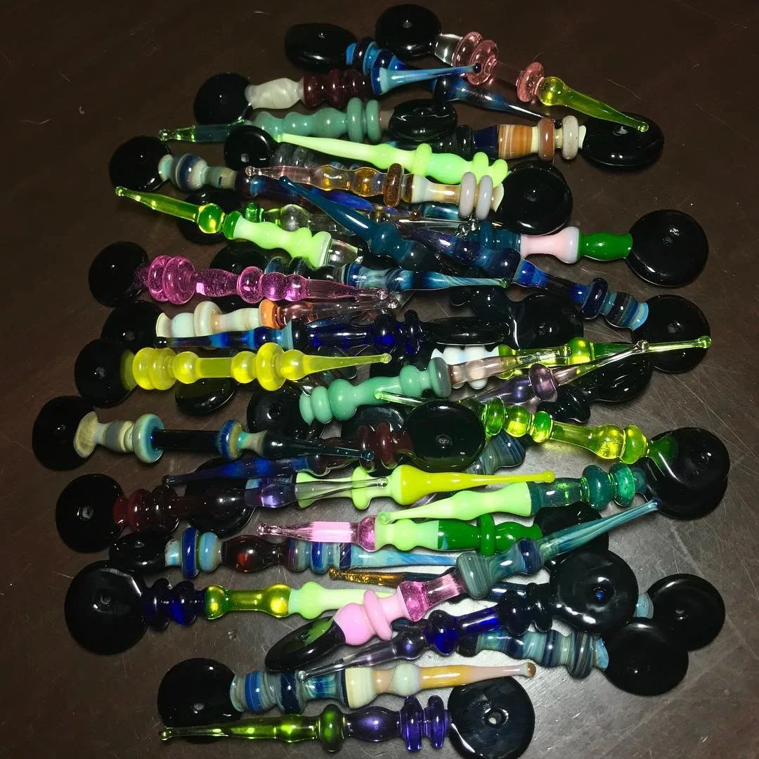 A collection of colorful glass blowing pipes on a dark surface.