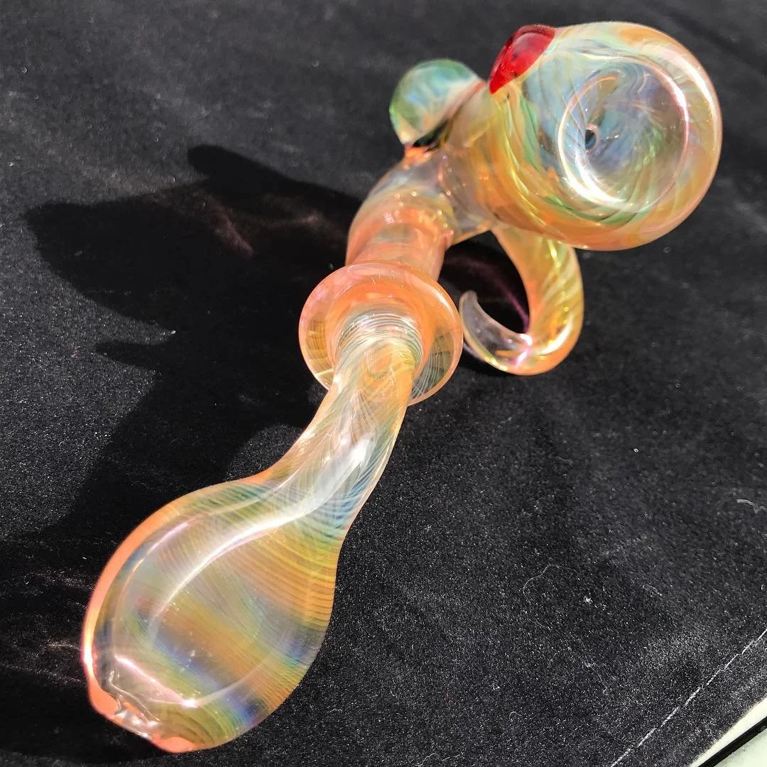 Colorful glass hand pipe on black surface.