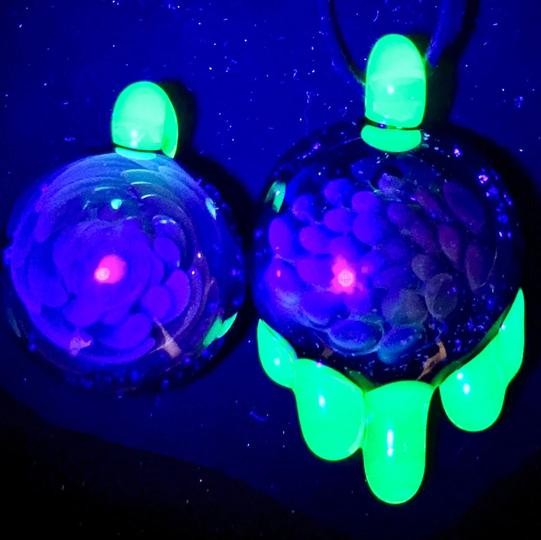 Glow-in-the-dark decorative objects resembling purple insects with green accents, illuminated under black light.