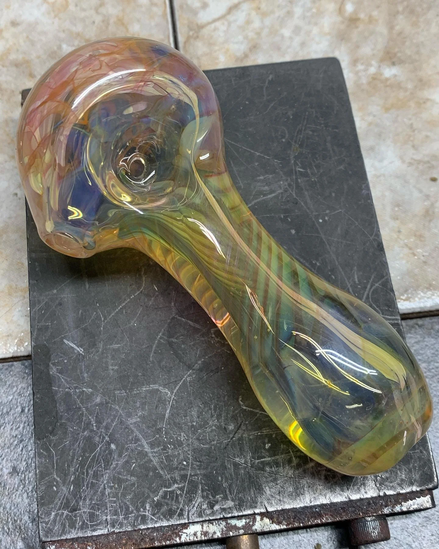 Colorful glass sculpture of a bird's head and beak, resting on a black surface.