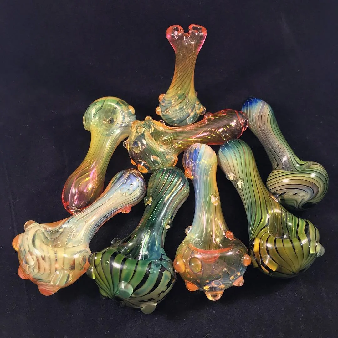 Colorful glass paperweights with elongated, twisted shapes and striped patterns on a black background.