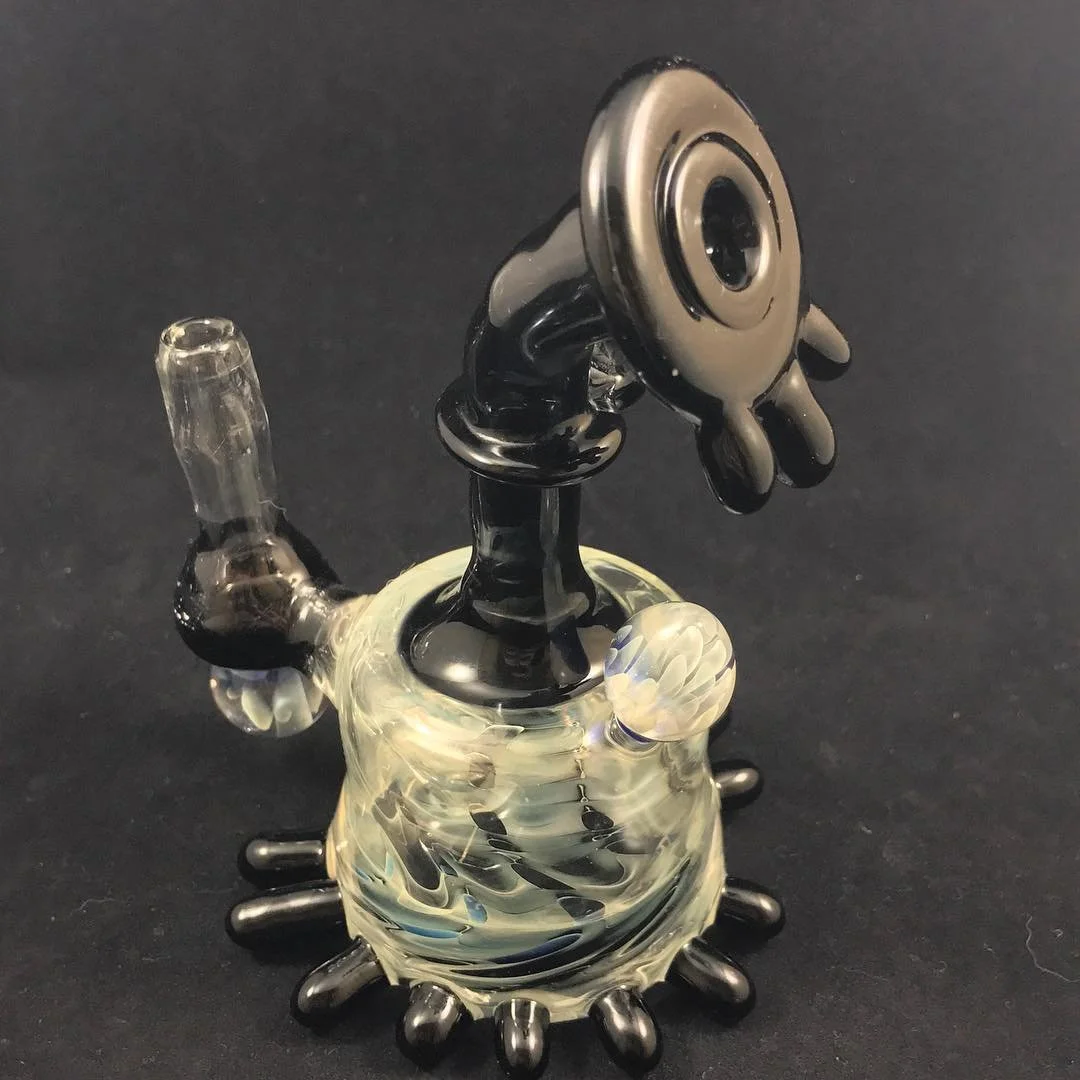 Glass pipe in the shape of a cartoon character with a smoky eye, black limbs, and a bleached white body, on a black background.