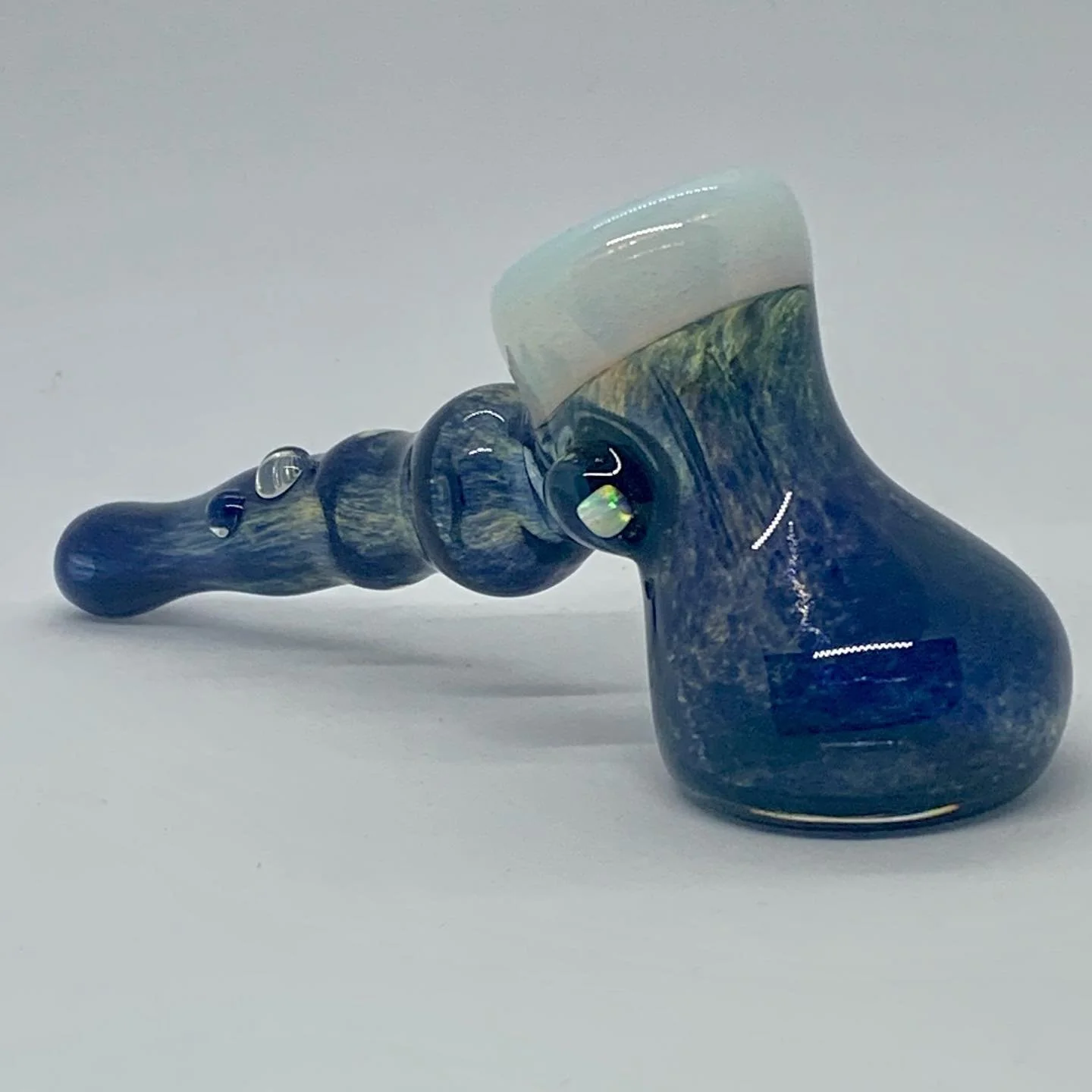 Colorful glass pipe with a blue and yellow marbled design, lying on a white surface.