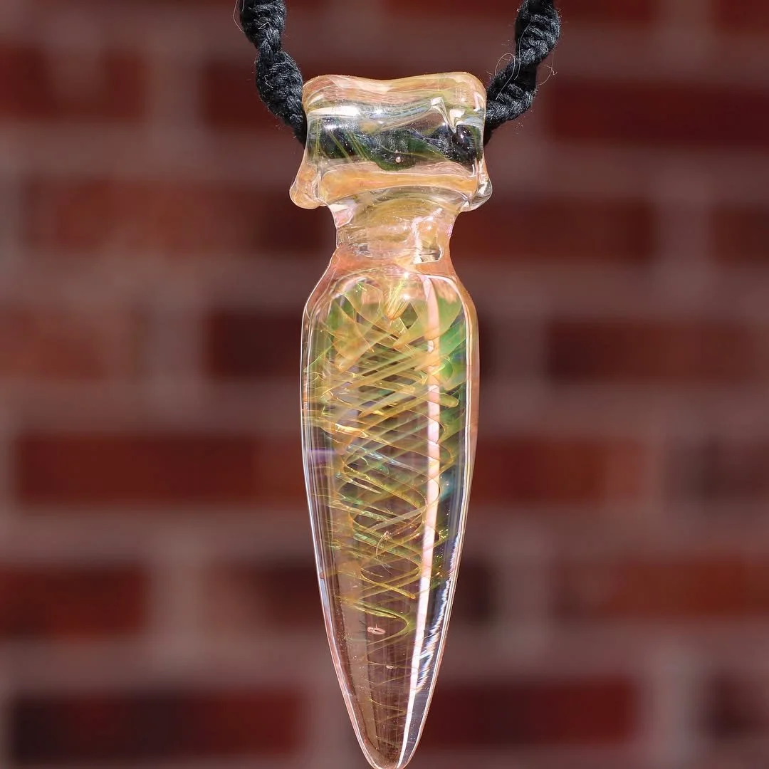 A glass pendant necklace shaped like a dagger with a spiral pattern inside, hanging from a black cord.