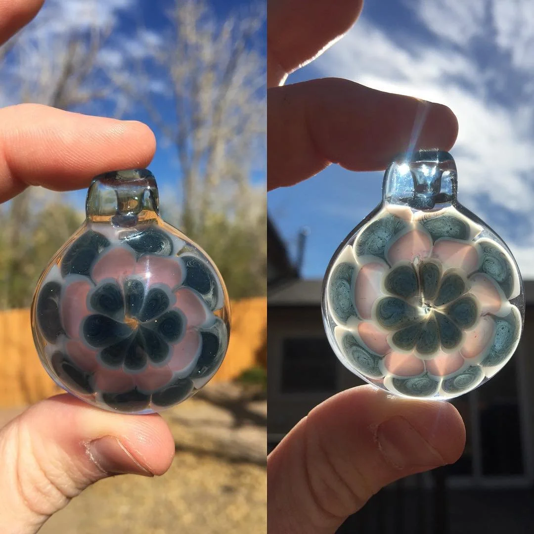 Glass pendant with layered floral pattern, shown outdoors against a blue sky and with sunlight.
