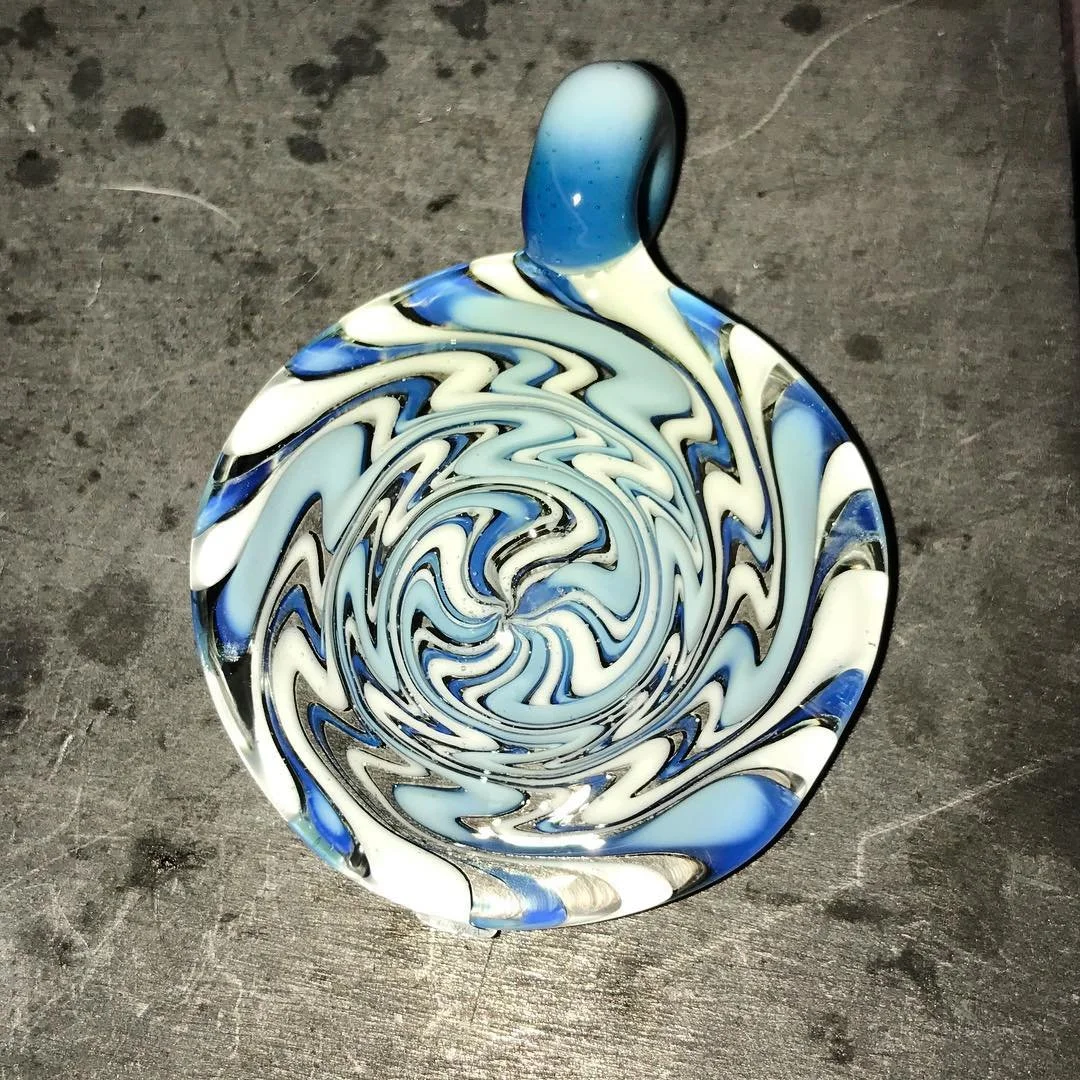 A colorful glass bowl featuring a swirling pattern of blue, white, black, and clear glass.