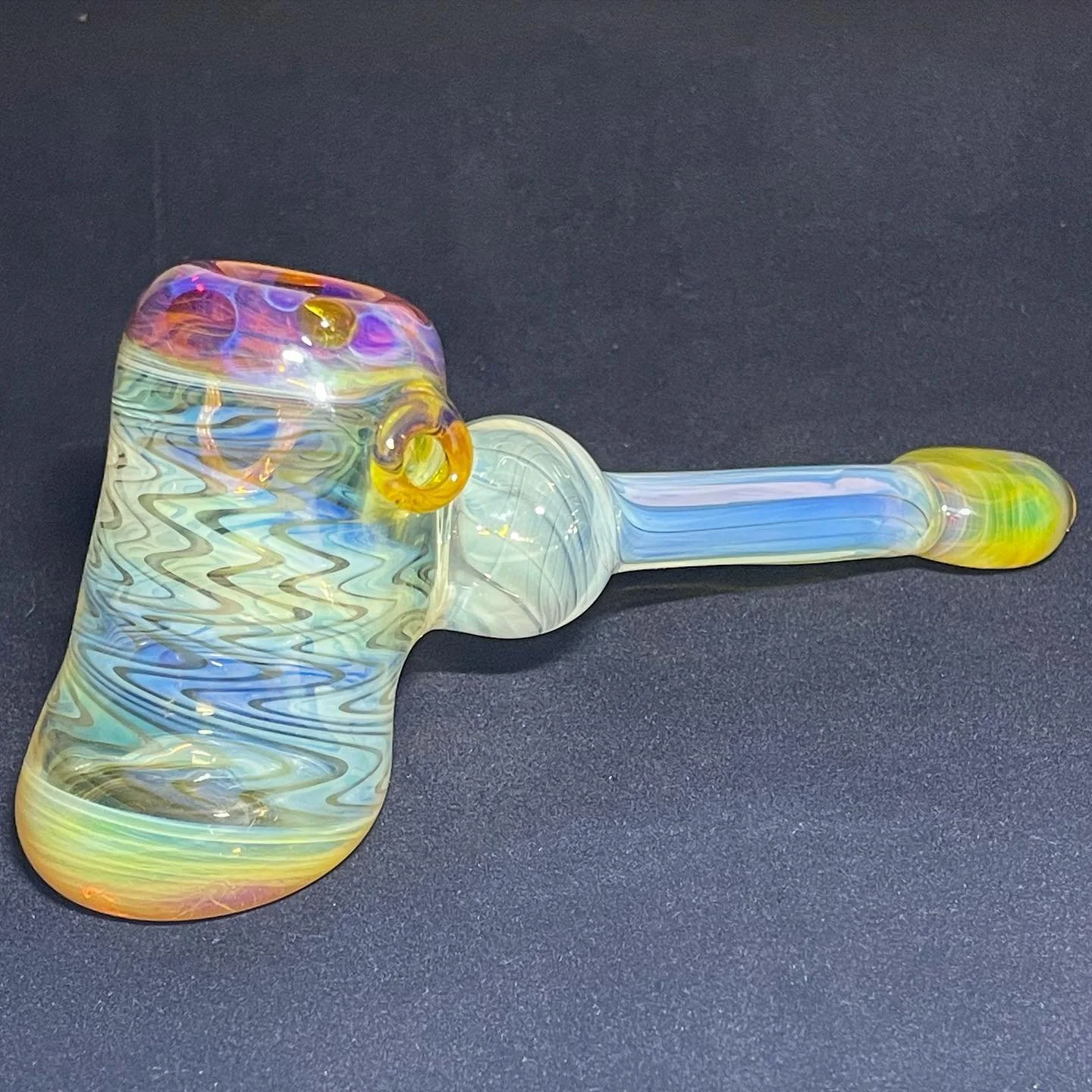 Colorful glass pipe with a swirling pattern on a black surface.
