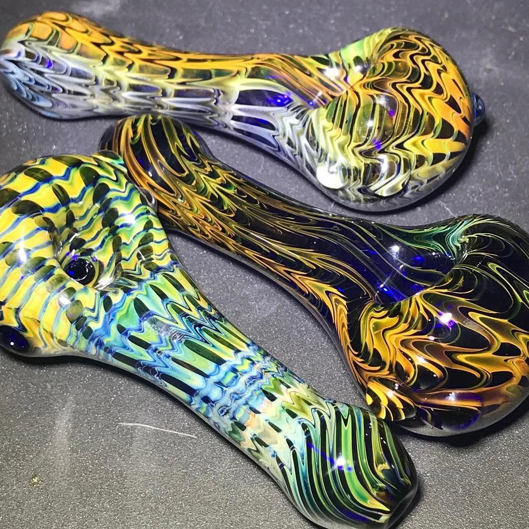 Two colorful, abstract glass sculptures with swirling patterns, placed on a dark surface.