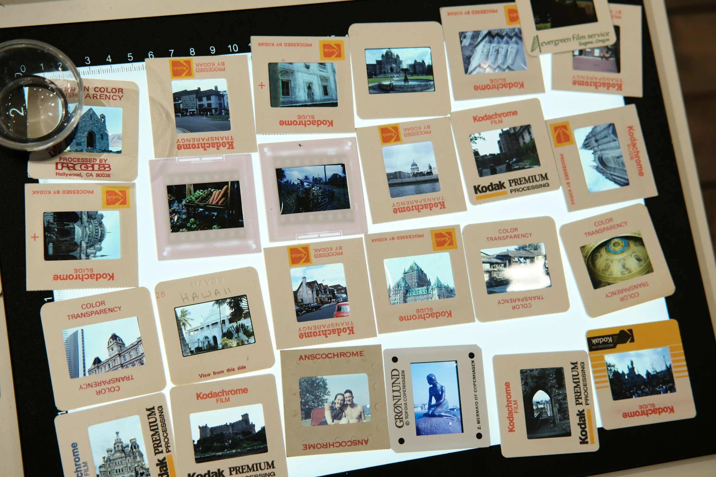 A contact sheet of multiple vintage photographic slides, some labeled 'Kodachrome' and 'Kodak'. The slides contain images of landmarks, buildings, and scenes from various locations including Hawaii and Washington, with some marked as 'Processed by Ko
