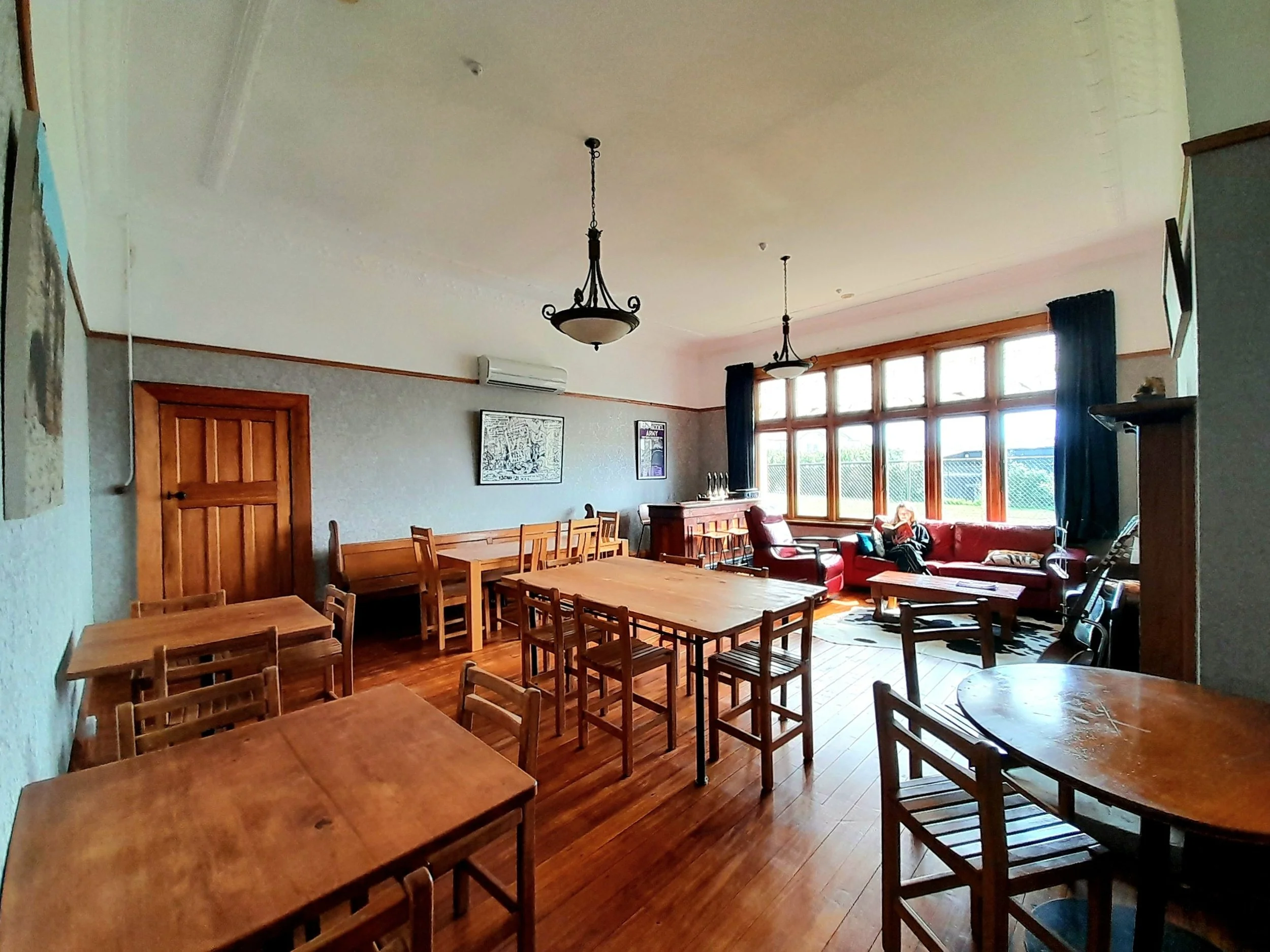 Heritage flashpacker dining room with a stylish mahogany bar, leather sofas, and cowhide accents in Greymouth, West Coast, New Zealand.