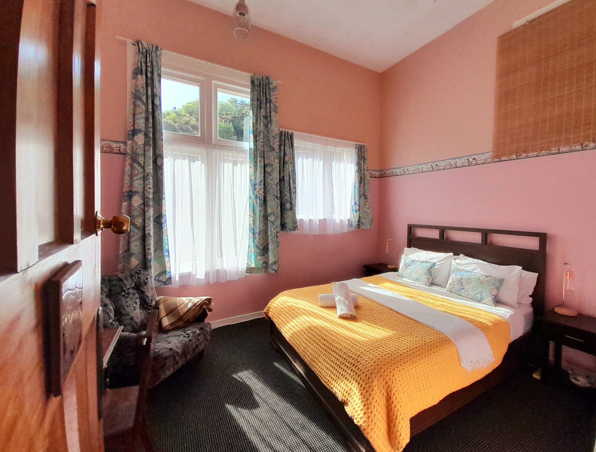 Standard private rooms at Noah's Ark Flashpacker feature queen size bed, bed side tables, copper lamps with Edison bulbs, cozy armchair and small desk with chair.