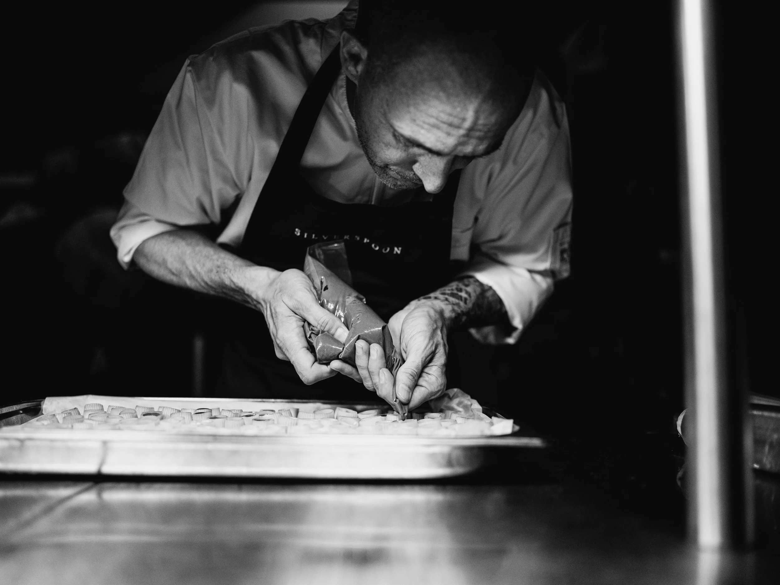 Een zwart-wit bedrijfsfoto van een kok die een bord opdient. Door een professionele fotograaf uit Eindhoven. 