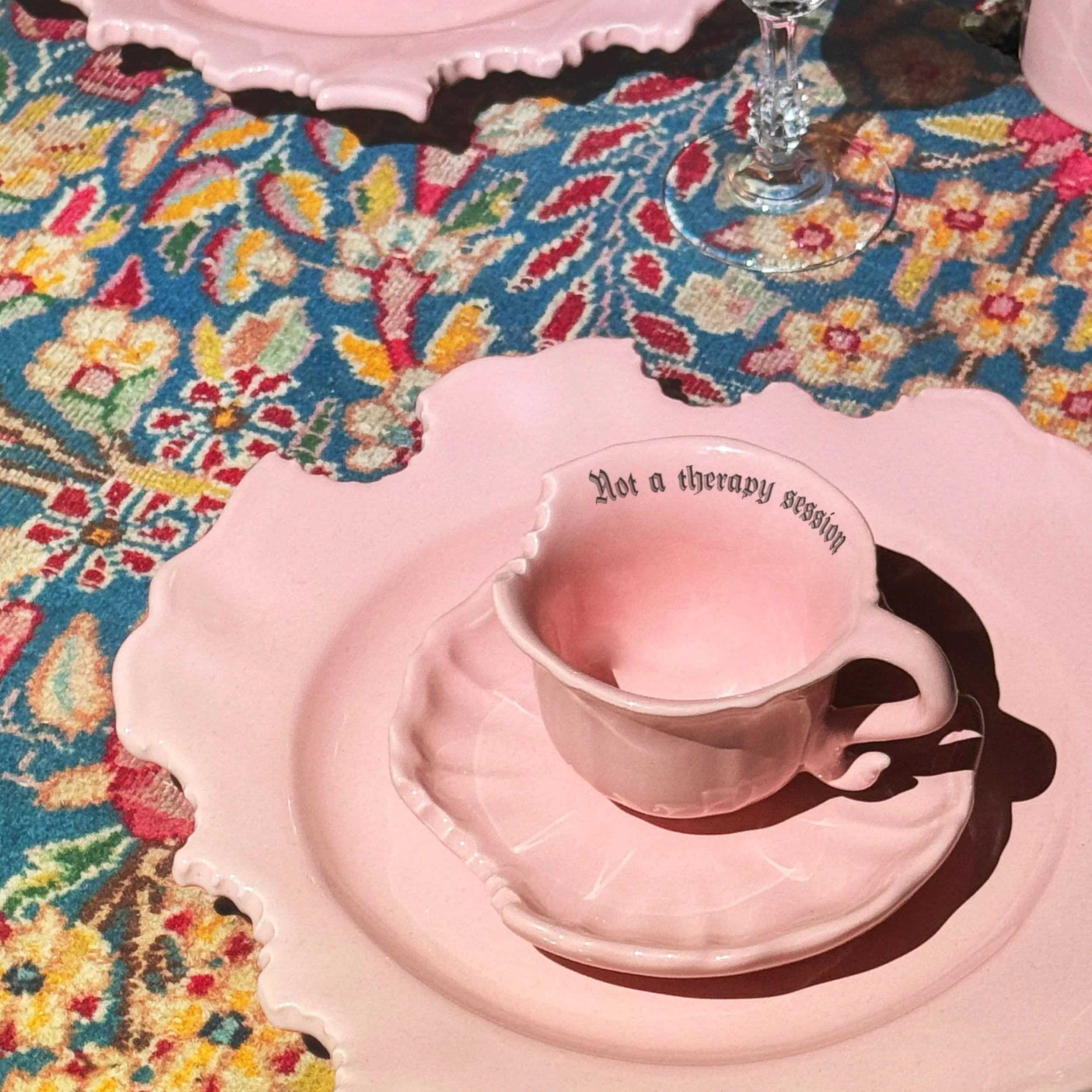 Multiple pink layered ceramic dishes or trays with decorative edges, placed on a colorful patterned carpet.