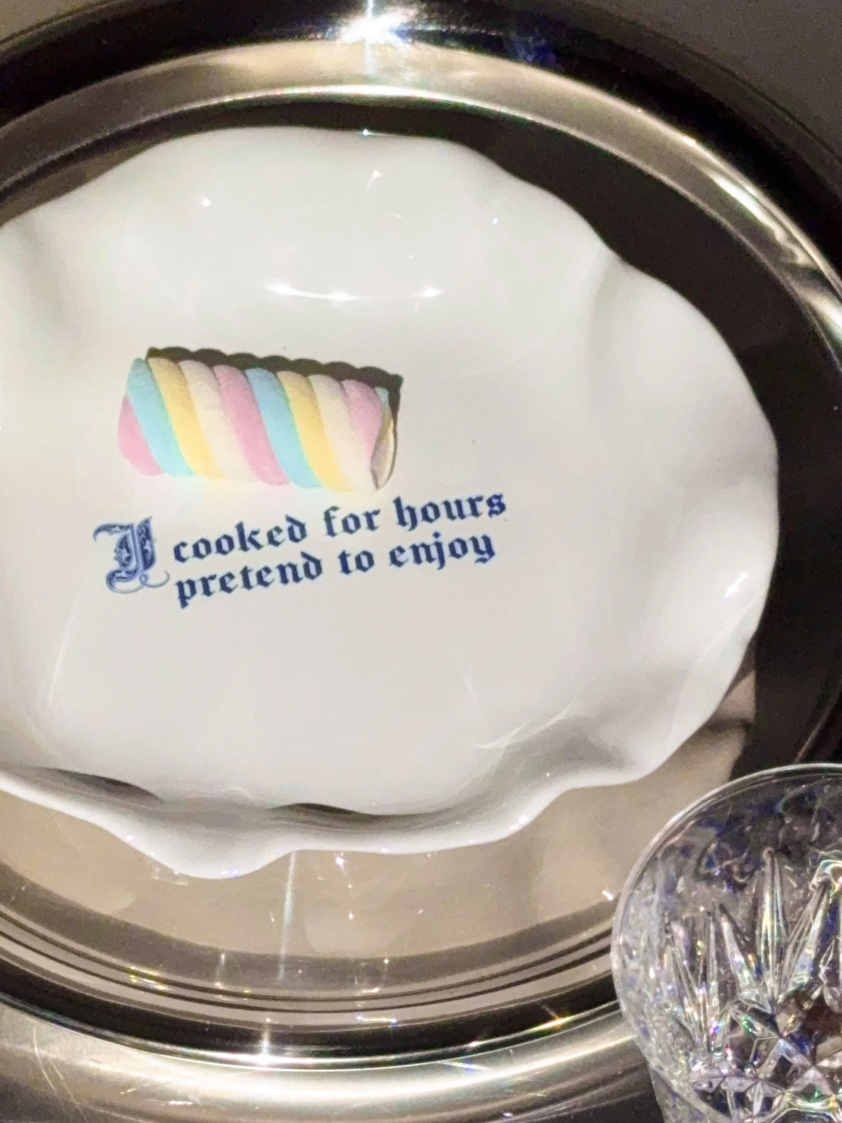 A white plate with a colorful marshmallow on it and the text 'I cooked for hours pretend to enjoy.'