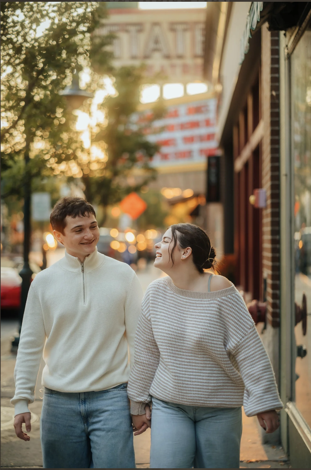 Romantic engagement session shot of couple walking under State Theater sign in Traverse City Michigan