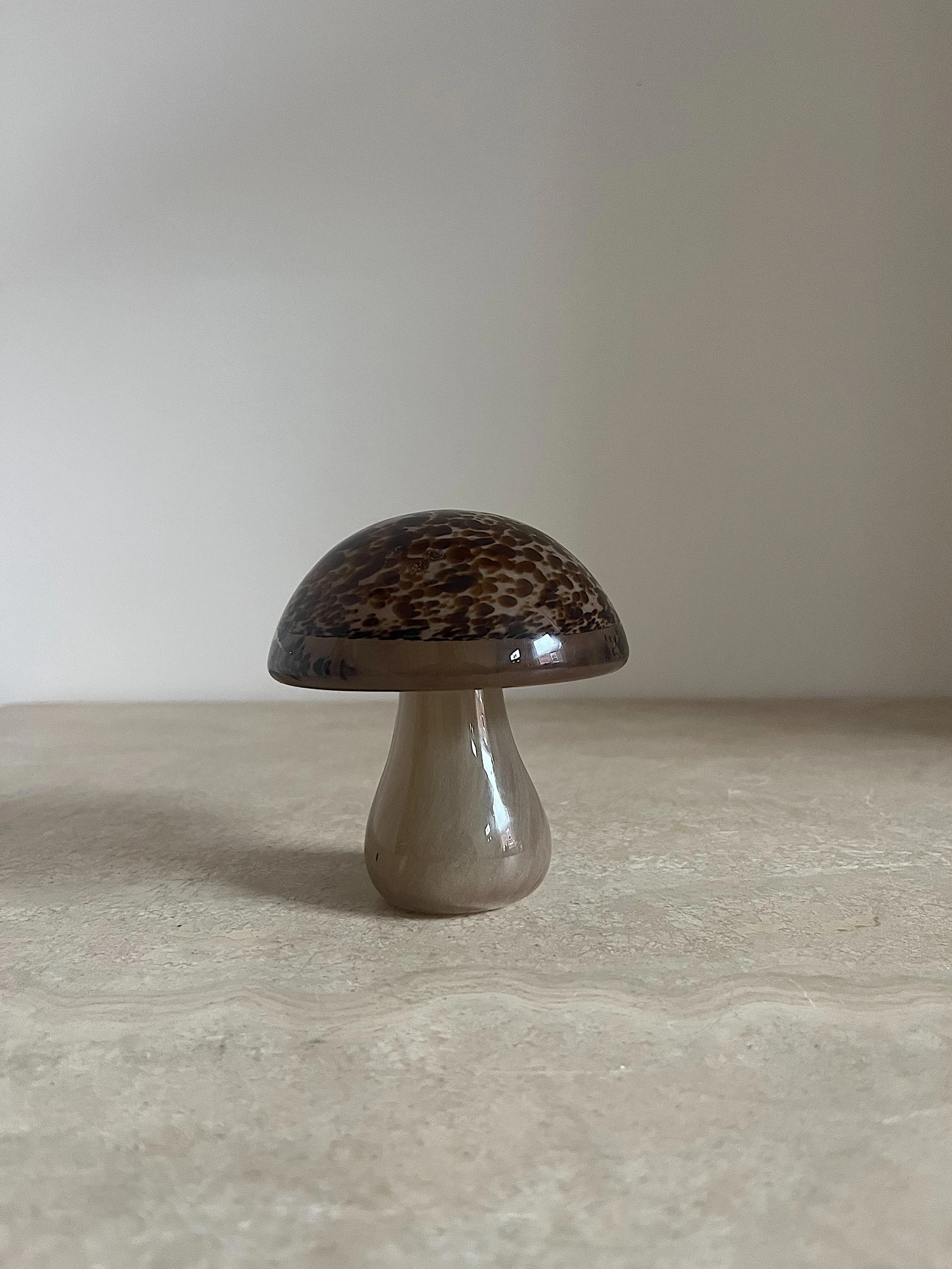 A ceramic mushroom ornament with a brown speckled cap on a light surface.
