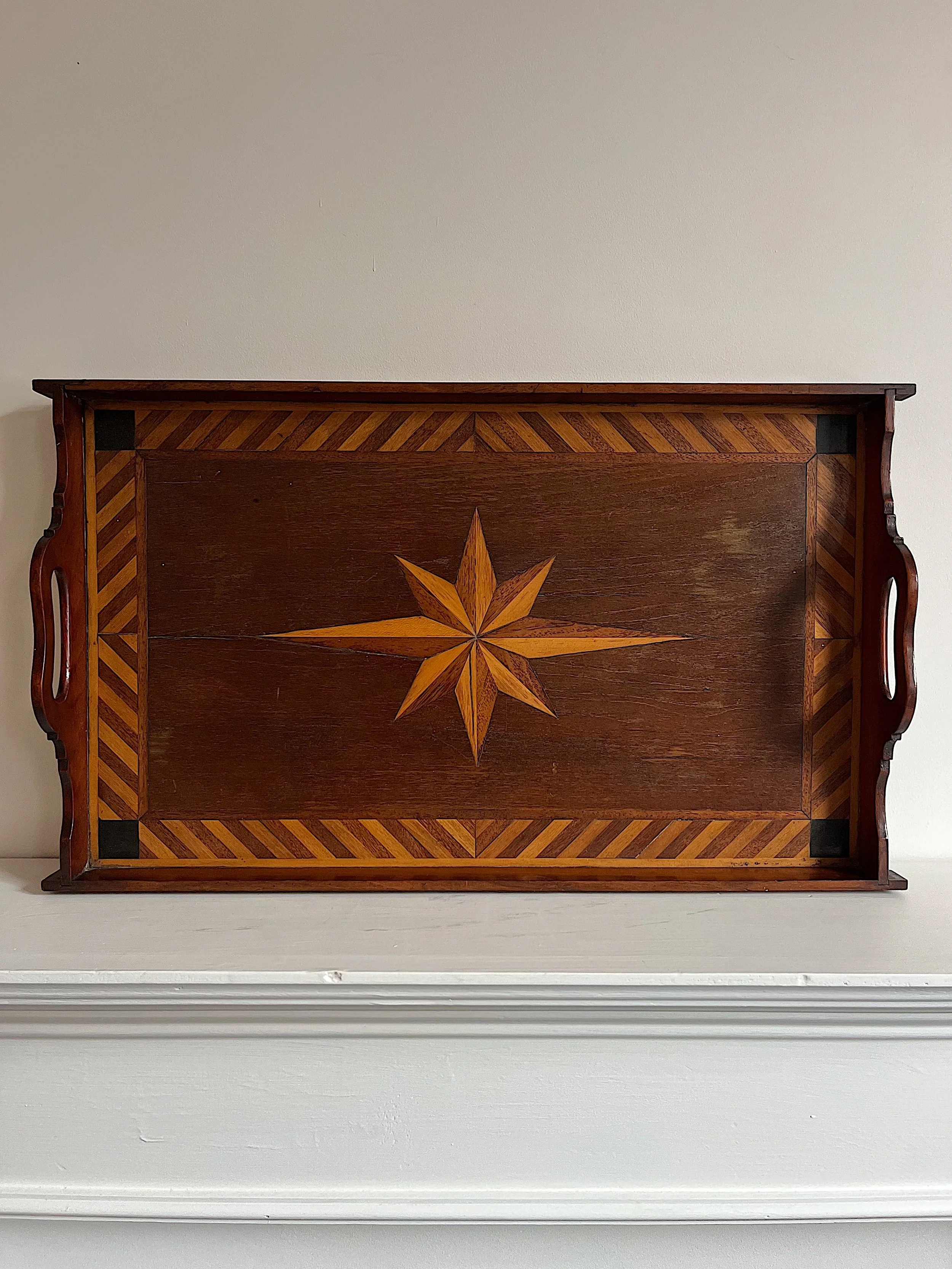 Wooden tray with star inlay design and chevron border, featuring side handles.