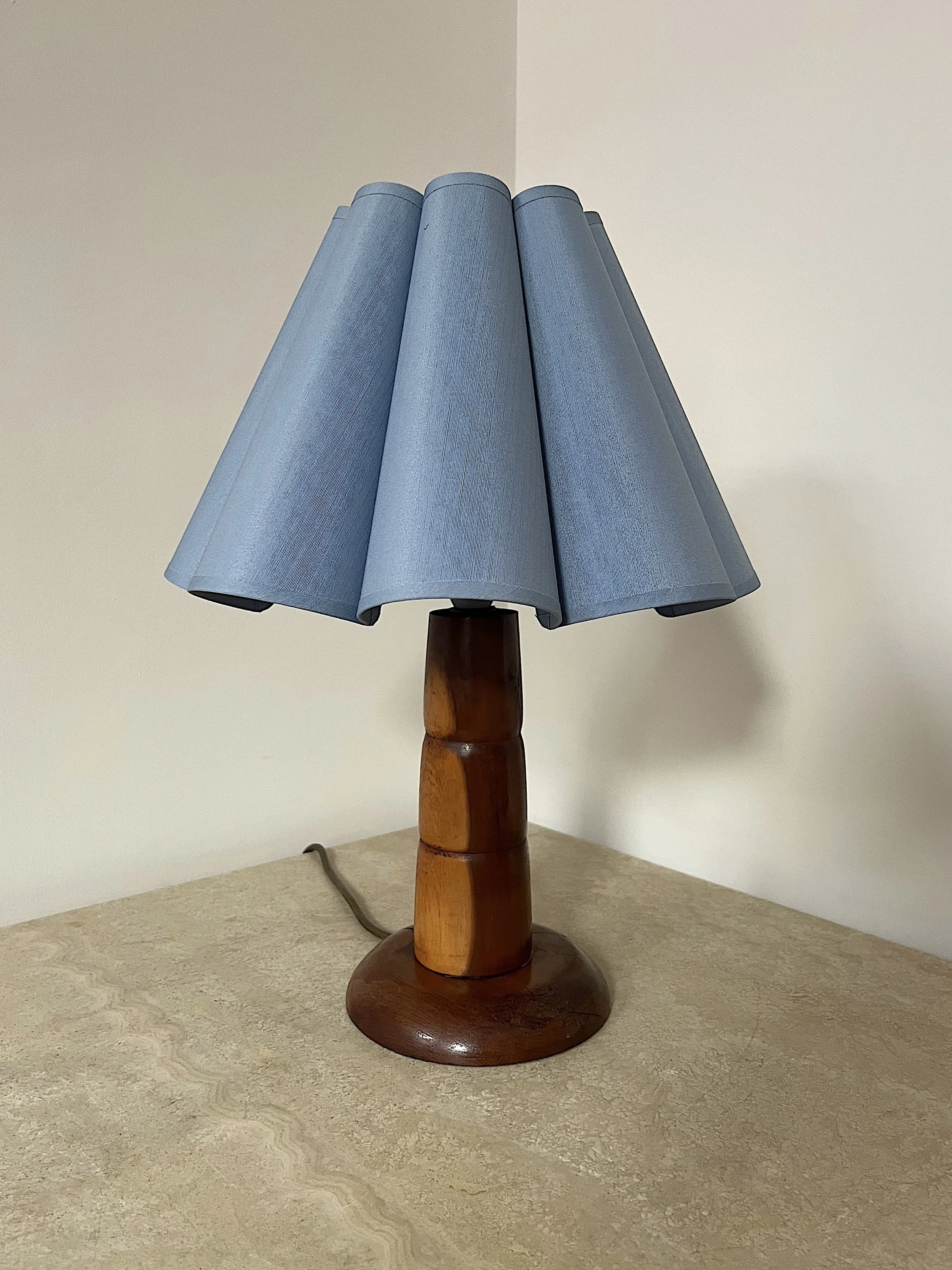 Vintage wooden lamp with blue conical lampshade on a light-colored table.