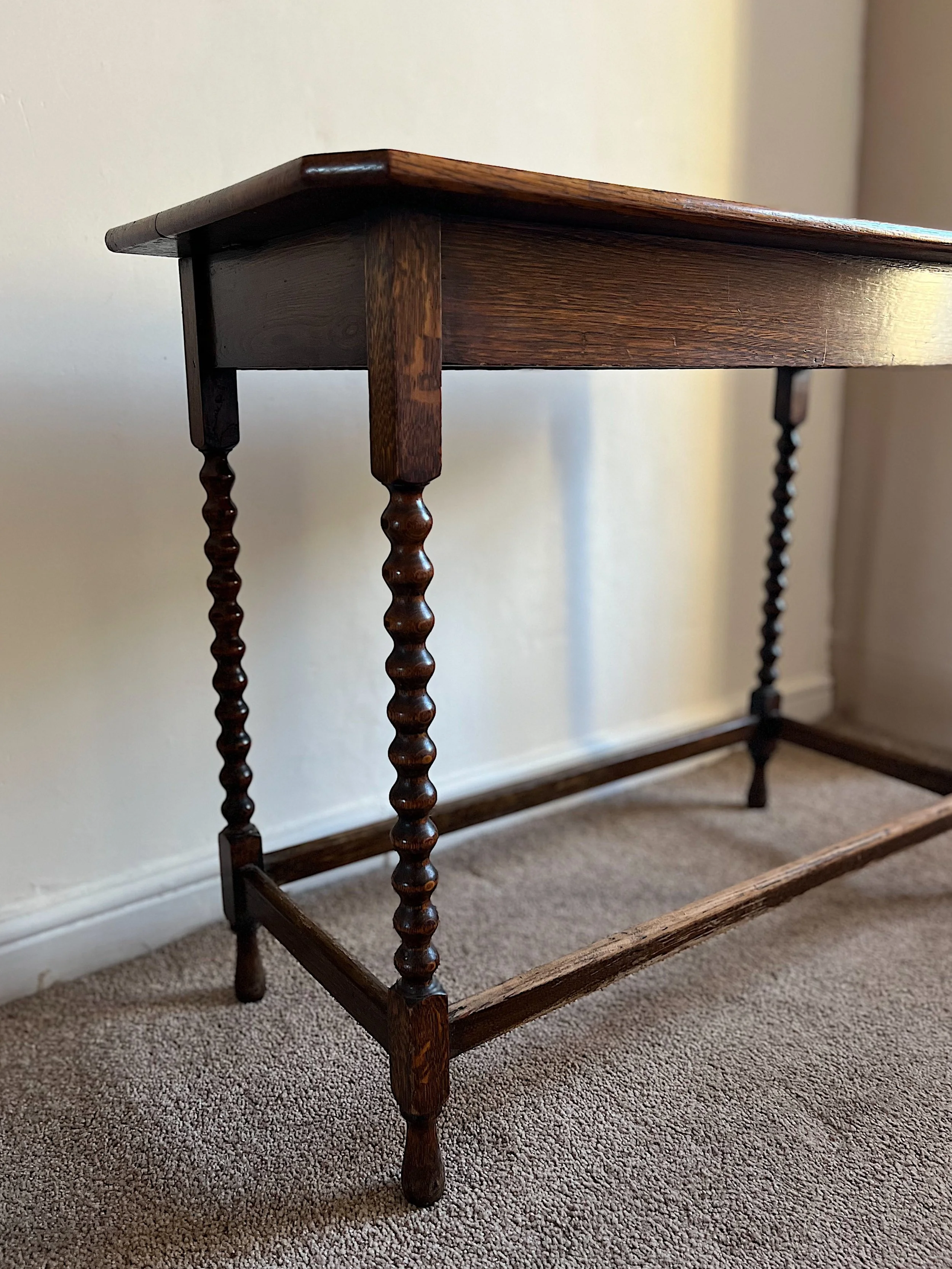 Wooden table with carved spiral legs on a carpet.