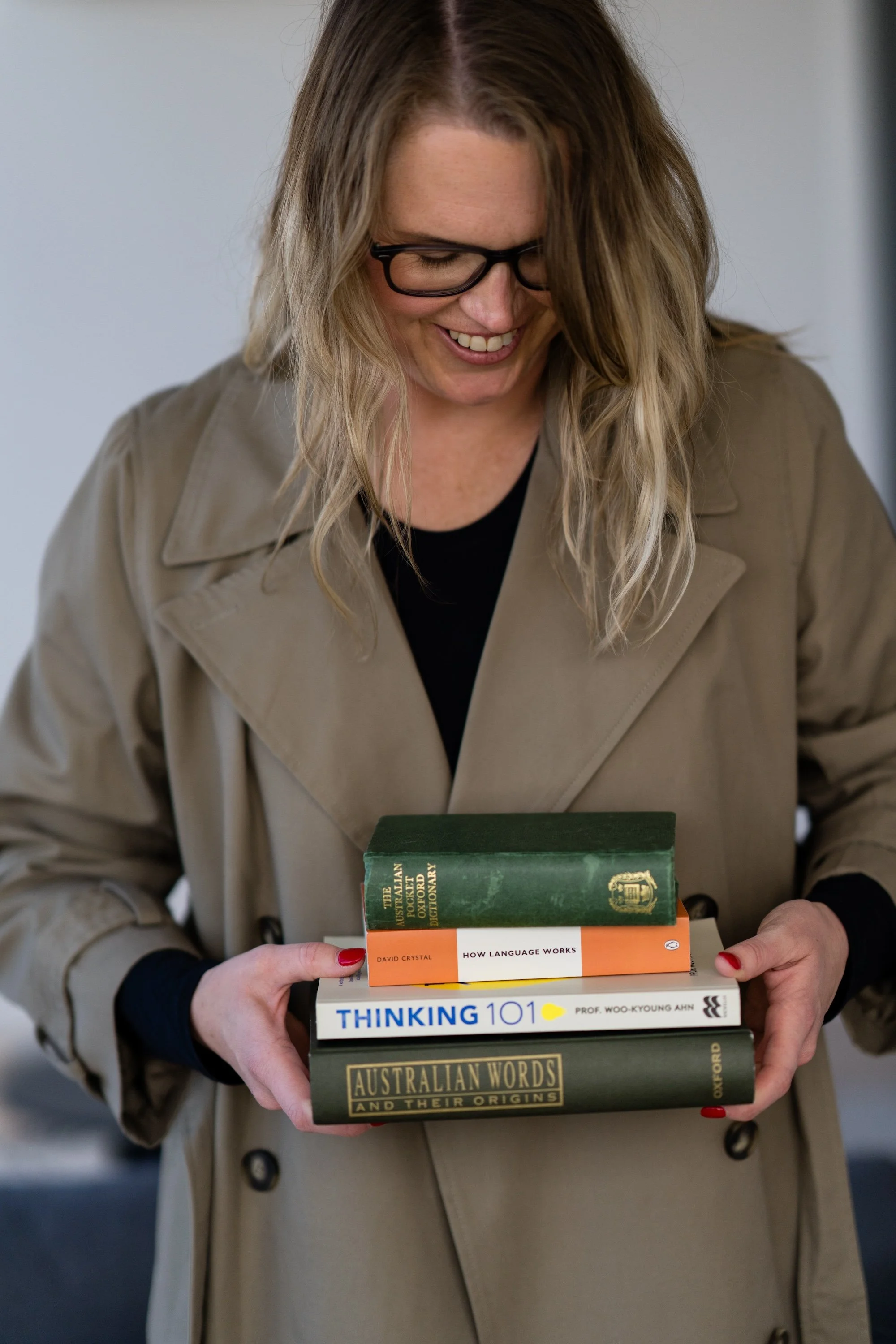 Kathy Rast stands holding a small stack of books relating to Language and Words