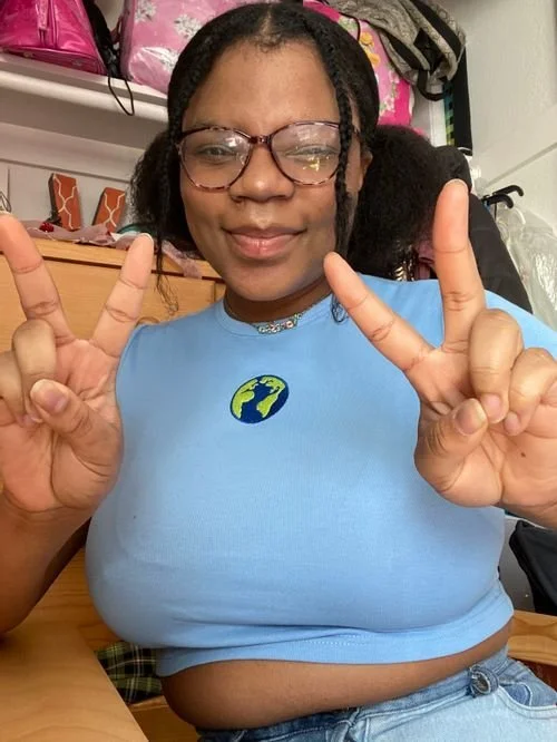Vanessa Campbell of Nessacrafts making peace signs in a blue crop top