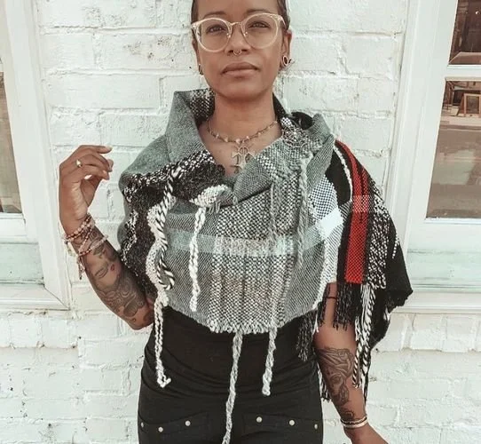 Adémigua Dixon of Prema Witch Handmade wearing a gray, black and white plaid woven shawl with fringe
