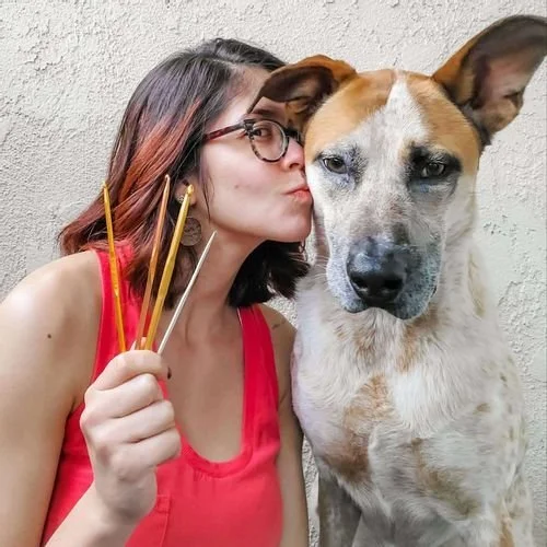 Veronica Sosa Robinson of Sosaprised Crafts & Canines kissing a dog while holding knitting needles