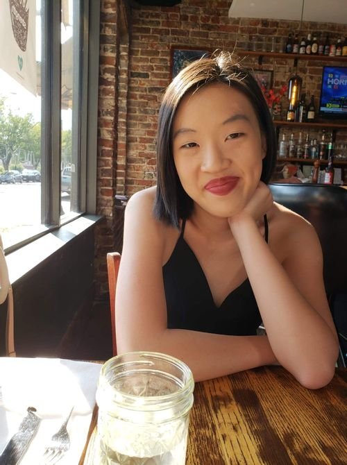 Cheryl Leow of Chronicles of Cheryl smiling at a restaurant table in a black top