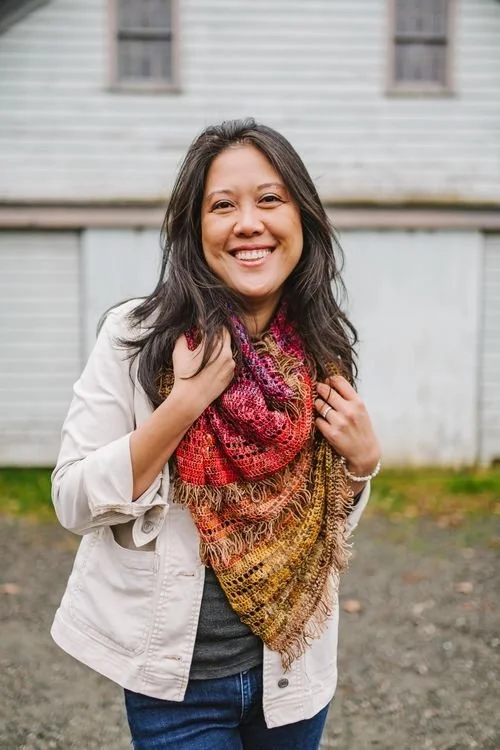 ChiWei Ranck of One Dog Woof smiling in a cream jacket and a red and gold scarf
