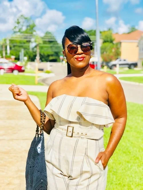 Nkese Lewis of Cosmic Creations N' Designs in a striped strapless jumpsuit with a blue crochet bag