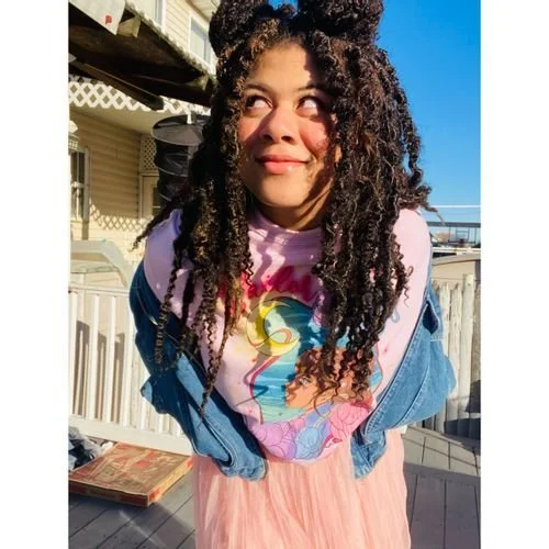 Amanda Solomon of MelanatedBohoBae in a rainbow graphic top, denim jacket and pink tulle skirt