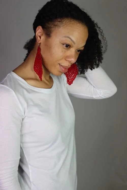 Aftan Mitchell of Afghans by Aftan in a white top and red fringe statement earrings