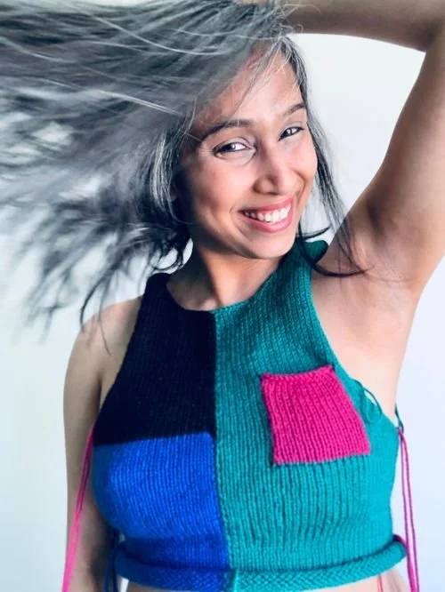 Deepsha Menghani of Yarns And Coffee smiling in a color-block knit halter top with a pink pocket