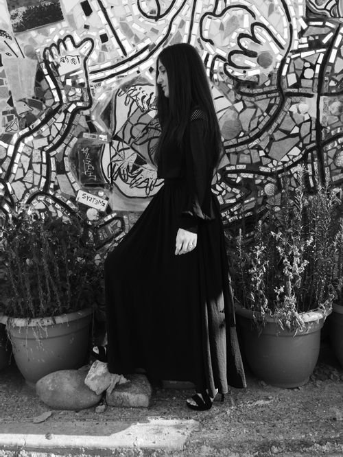 Ceylan Zehir of I'm that stitch in a long black dress against a graffiti mural, in black and white