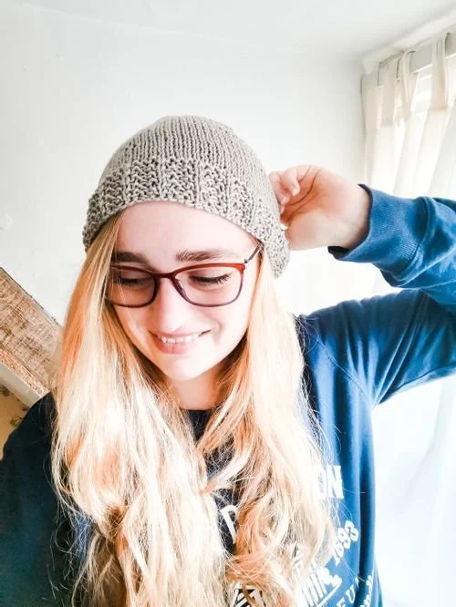 Olivia Startup of The Merry Mammoth in a taupe knit beanie and glasses