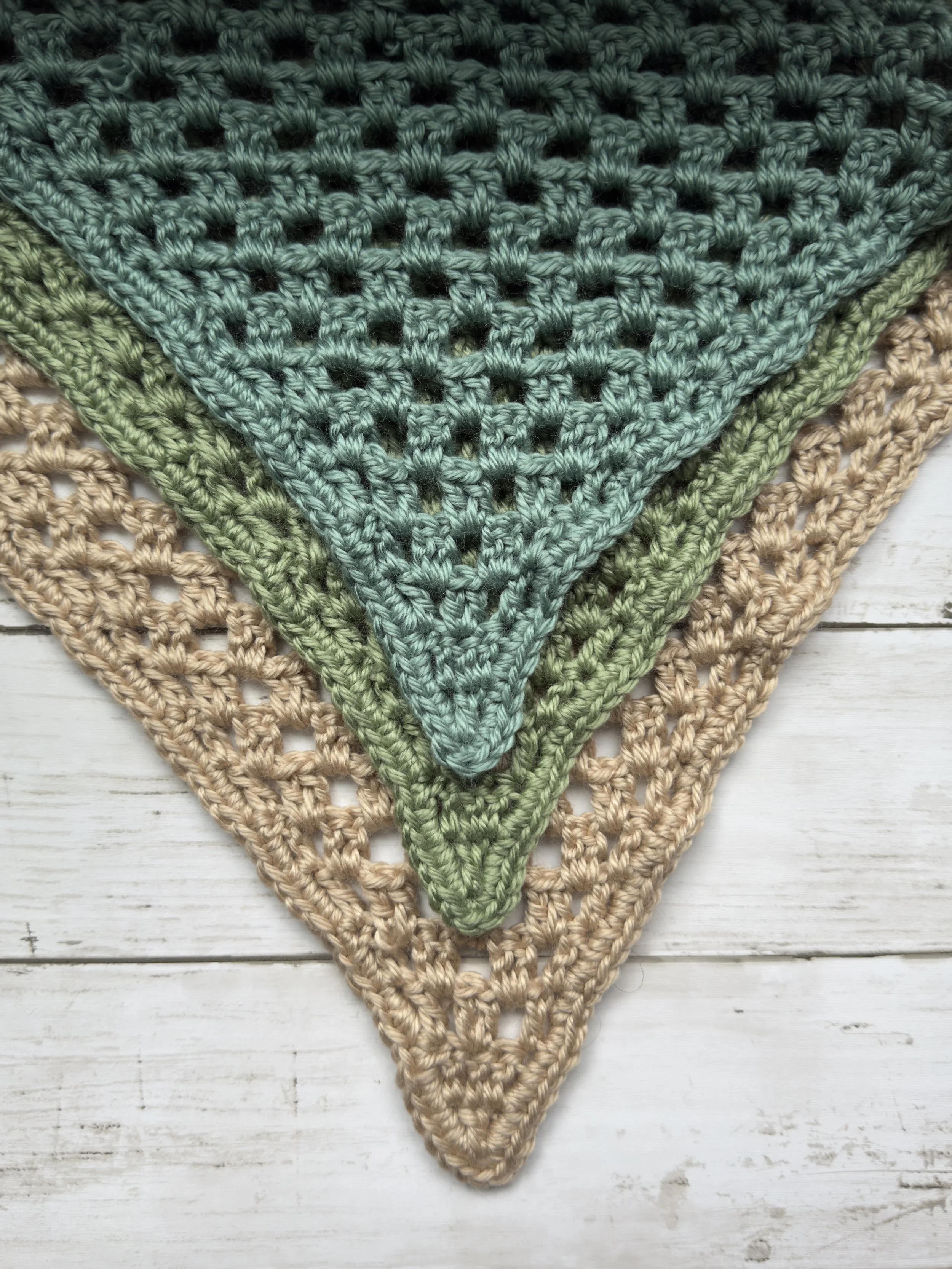 Close-up of three Easy Drape Bandanas layered in teal, sage and tan, showing the open mesh stitch pattern. Free beginner crochet bandana pattern.