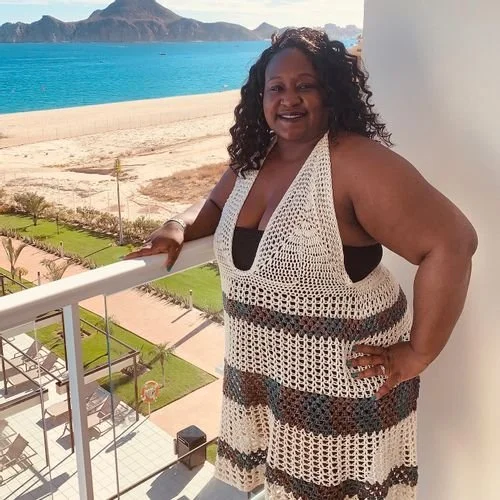 Rosalyn Bailey of Crochet Roze in a cream and gray striped crochet halter dress by the sea