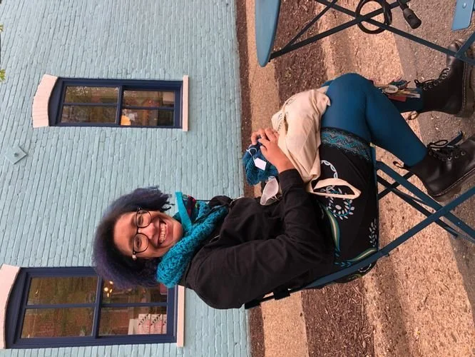 Kristen Jeffers of Kristpattern seated at an outdoor table in a teal cowl