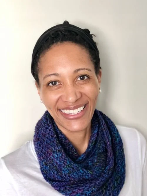 Marina Scott of Heart Bun Knits and More smiling in a navy and blue speckled knit cowl