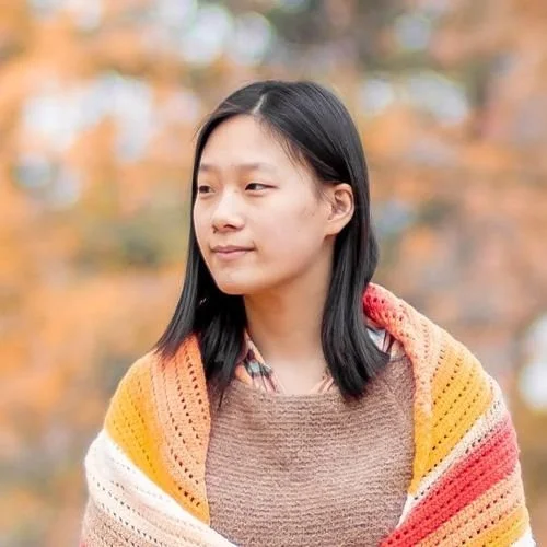 Julia Chiang of Little World of Whimsy wrapped in an orange, peach and cream striped shawl