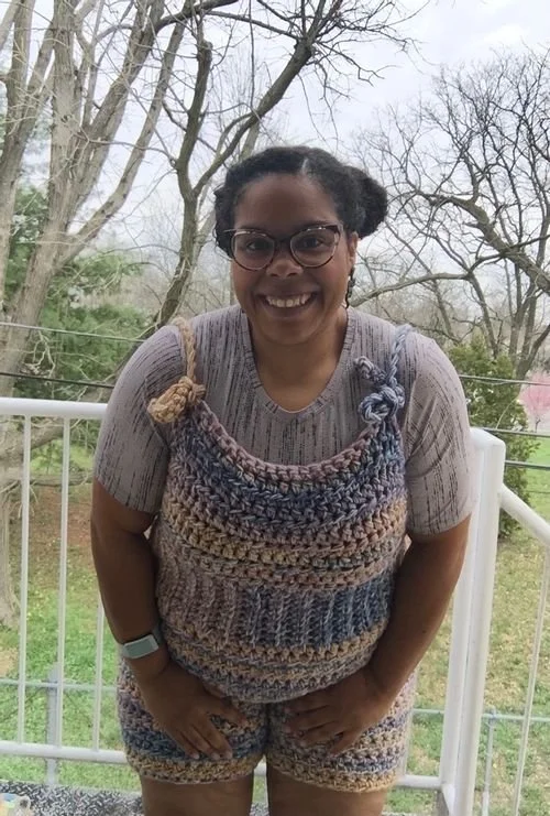 Aly Simmons of Knitislegit smiling in striped crochet overall shorts