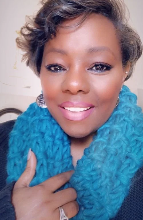 Elizabeth Myers of Liz Myers Knitwear smiling in a chunky turquoise knit cowl