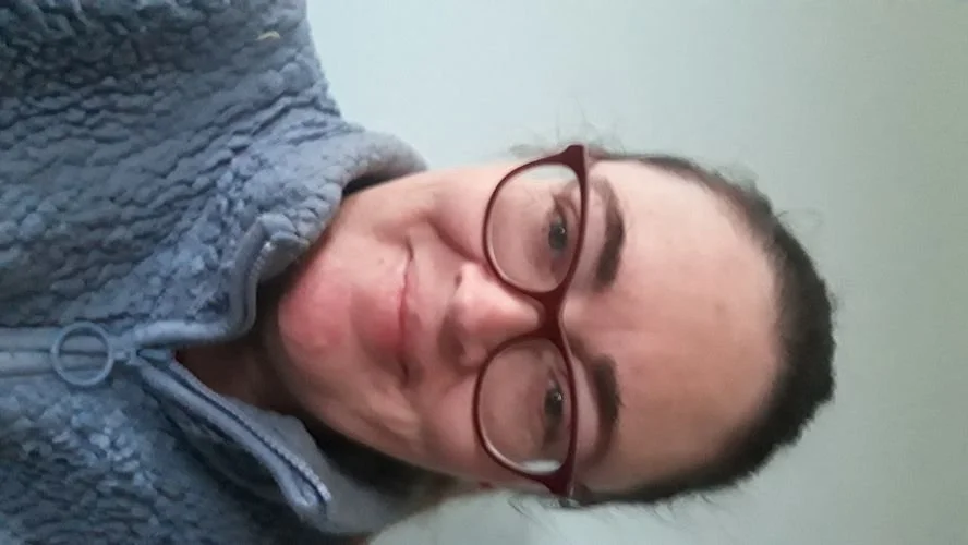 Michelle Mclaughlin smiling in red glasses and a gray hoodie