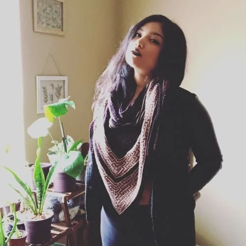 Claud Contreras of Audicee Arts wearing a black and pink knit shawl as a scarf