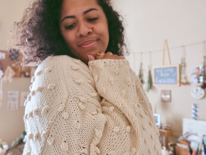 Gavriella Treminio of Hello Gavriella in a cream bobble-stitch knit sweater