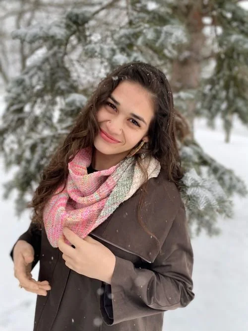 Shanti Nielsen of ShantiRoseFibreArts in a pink knit scarf and brown coat, smiling in the snow